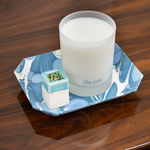 Candle labeled 'blue print' on a decorative tray with a small match holder on a wooden surface