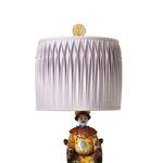 Decorative lamp with pleated lilac shade and ornate base on a white background