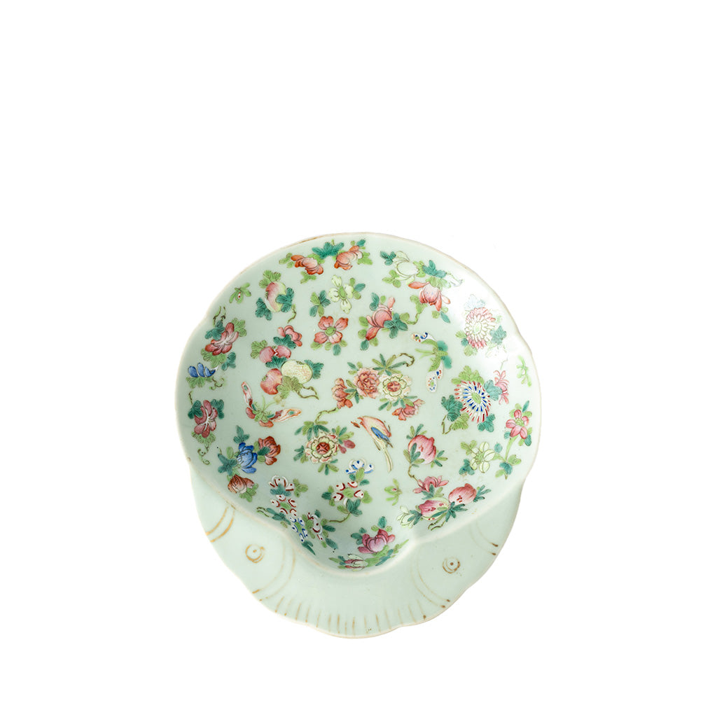 A small round ceramic bowl with a scalloped rim, decorated with a dense floral pattern in pink, green, and blue on a pale mint-green background, shown against a plain white studio background.