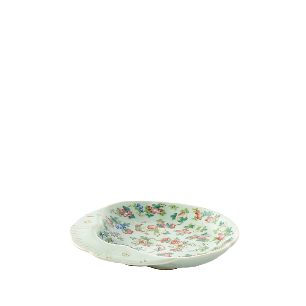 A small oval ceramic dish with a scalloped rim, decorated with a delicate multicolor floral pattern on a white background, isolated on a white studio background.