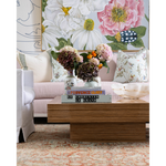 Rectangular wooden cocktail table with a thick, layered design and clean lines, styled with stacked books and floral.