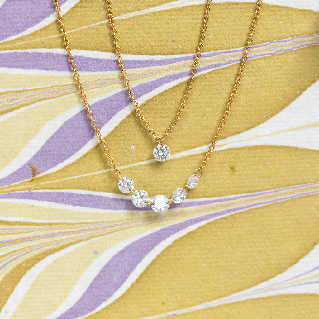 Gold necklace with clear stones on a yellow and purple patterned background