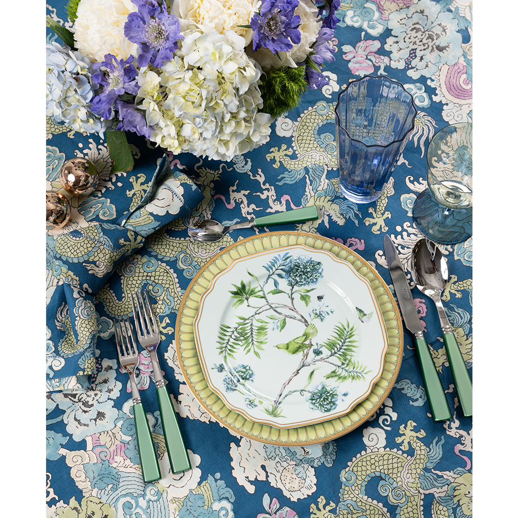 Set of six cobalt blue highball glasses with a vertical ribbed texture on a floral patterned tablecloth.