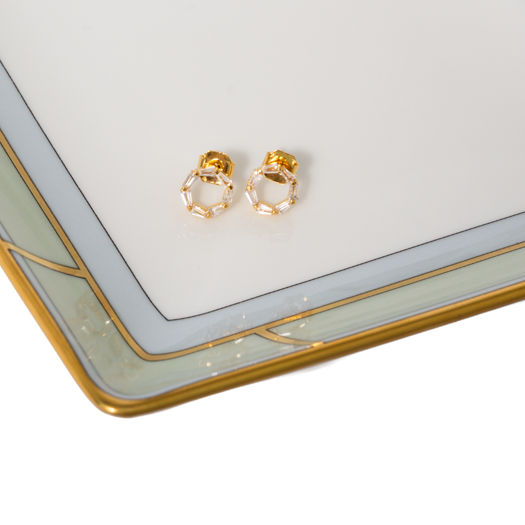 Gold hoop earrings on a decorative tray with geometric design