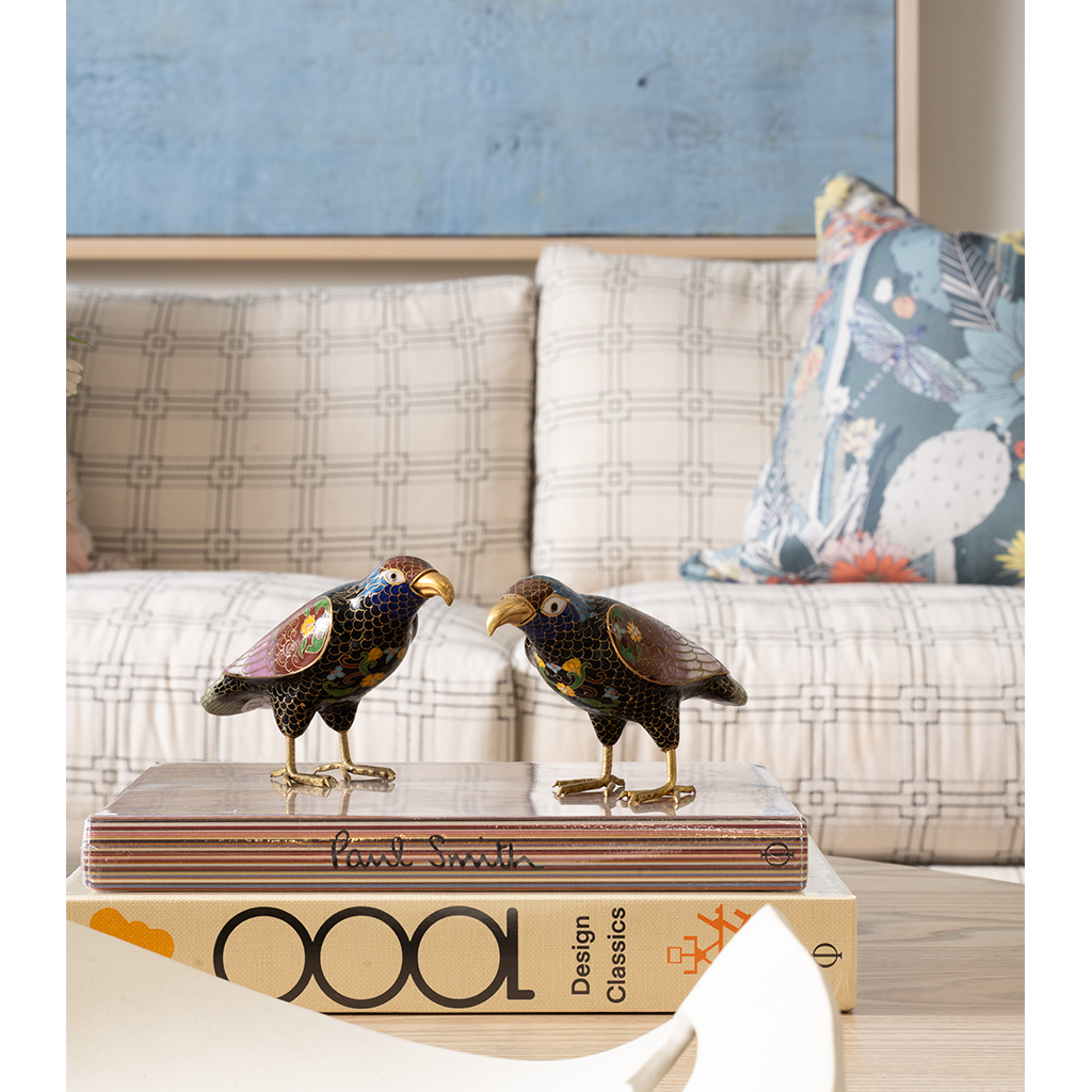 Beige plaid fabric sofa with square cushions and floral accent pillow in pastel tones.