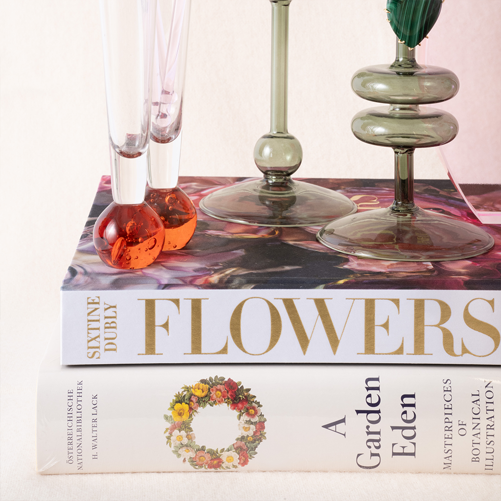 Book titled 'Flowers' with decorative glassware on a white background
