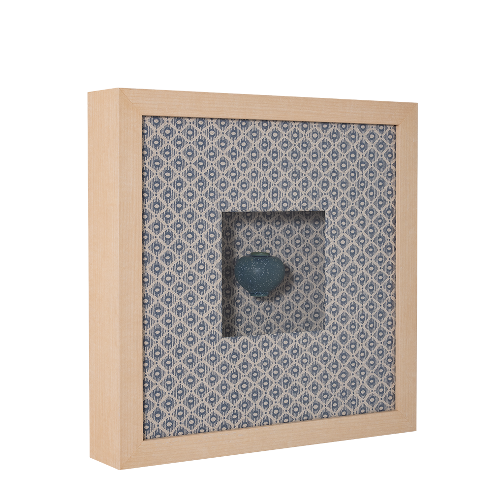 Decorative vase with a blue stone on a patterned fabric background