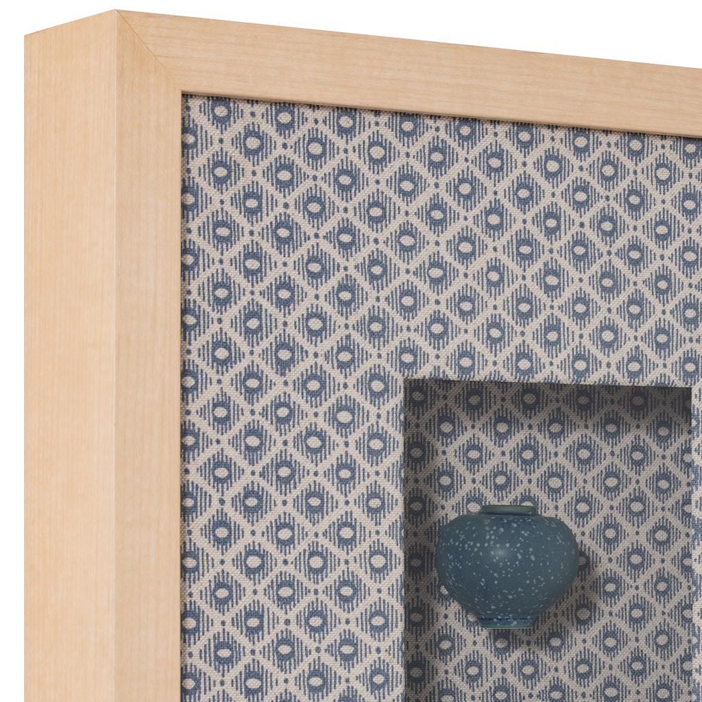Decorative frame with a blue patterned interior and a small blue vase inside.
