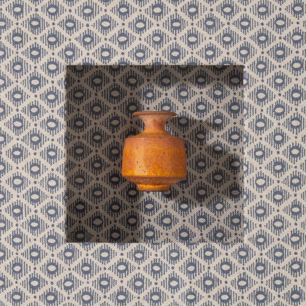 Small brown ceramic pot on a patterned fabric background