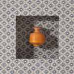 Small brown ceramic pot on a patterned fabric background