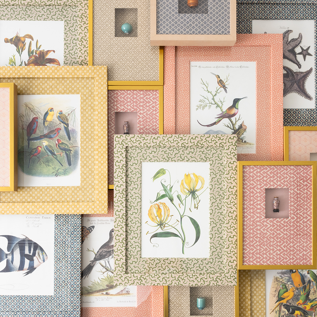 Collage of framed artwork with various patterns and subjects on a textured wall.