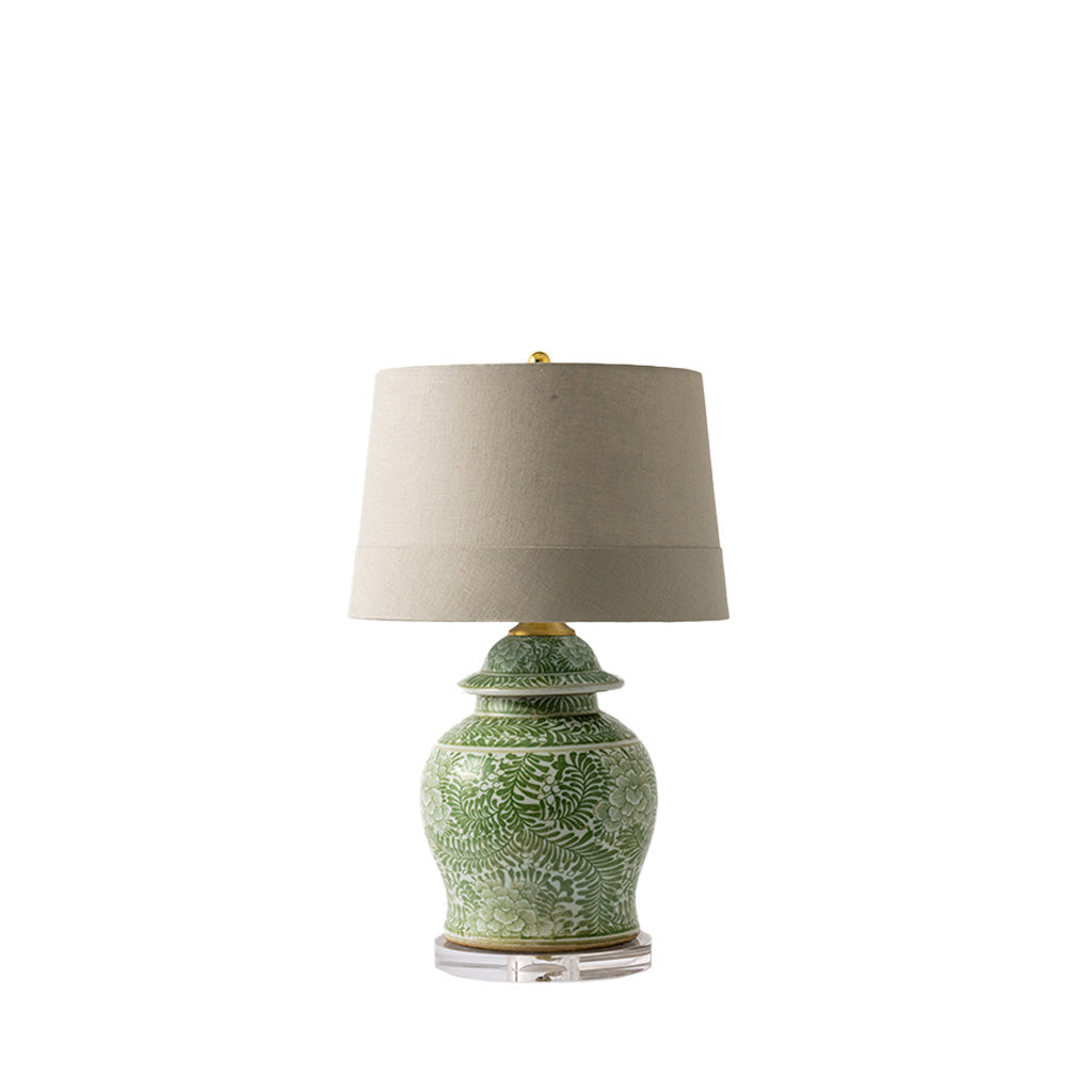 A table lamp with a green patterned ceramic jar base and a beige fabric drum shade, shown on a plain white background.