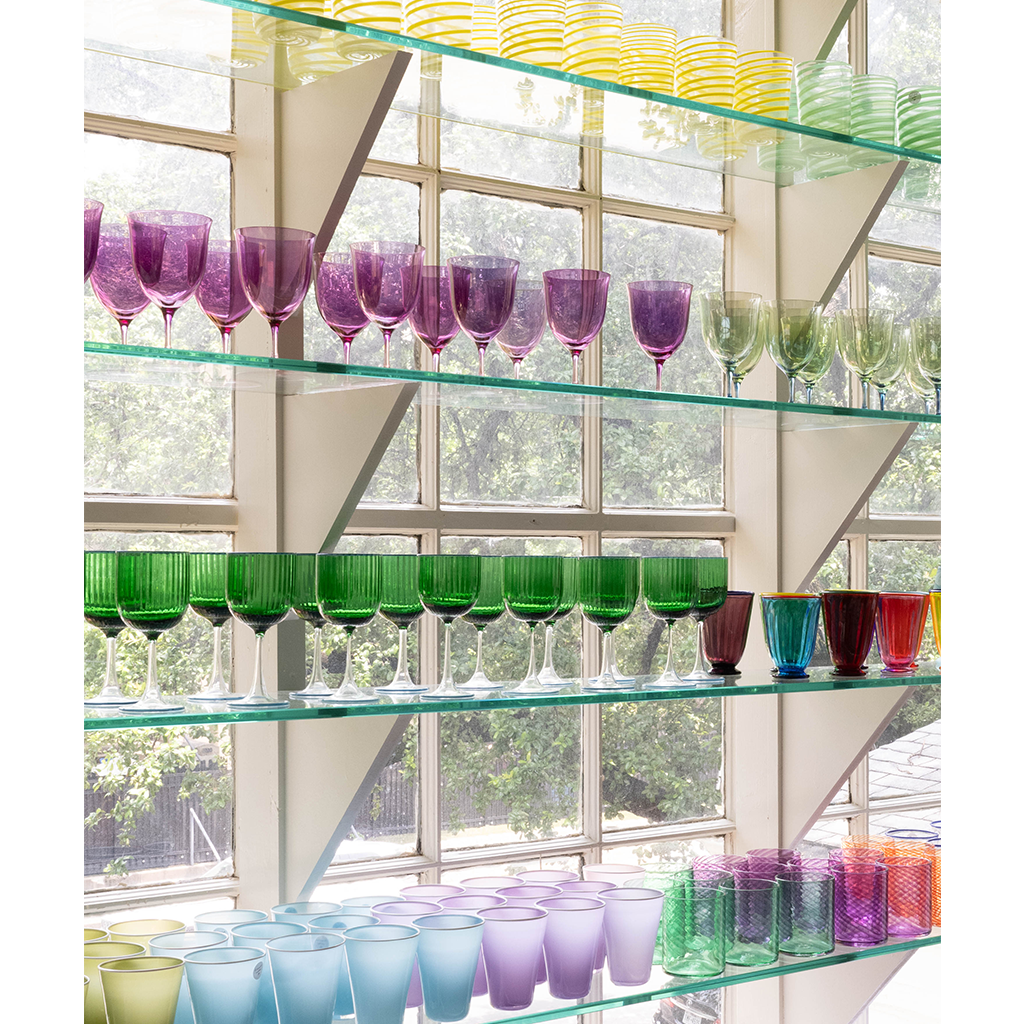 Glass shelves filled with colorful glassware in different shapes and sizes.
