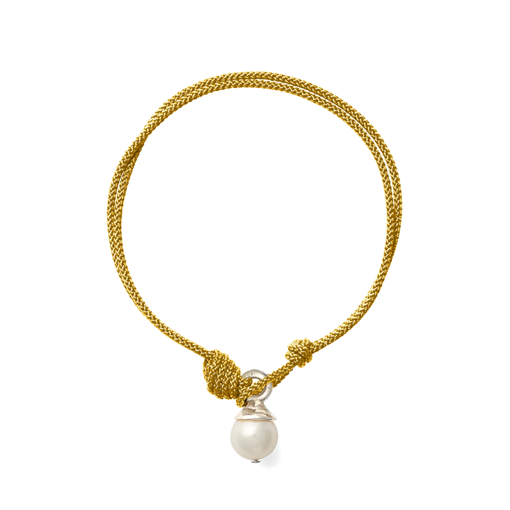 A gold braided cord bracelet with a knotted toggle closure and a dangling white pearl bead, shown on a plain white background.