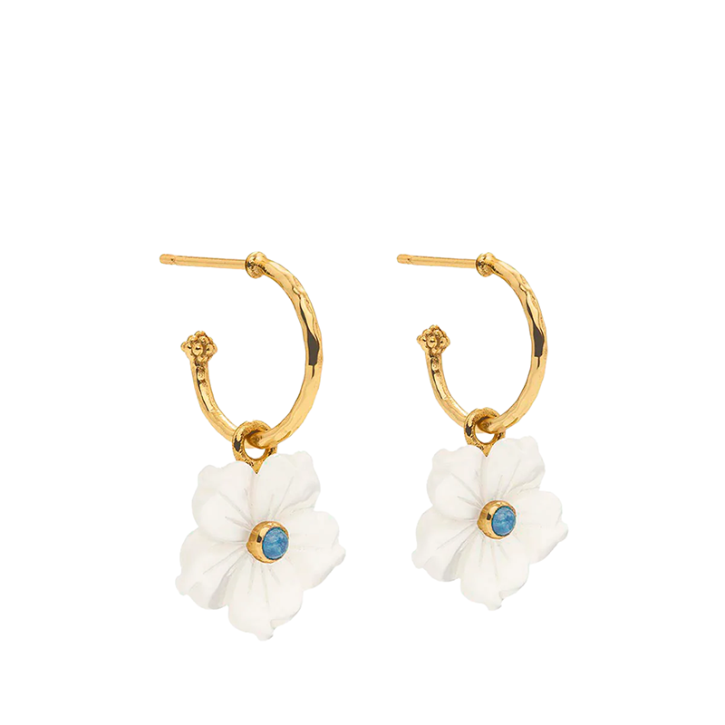 Gold hoop earrings with white flower charms and blue gemstones on a white background