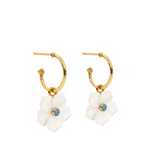 Gold hoop earrings with white flower charms and blue gemstones on a white background