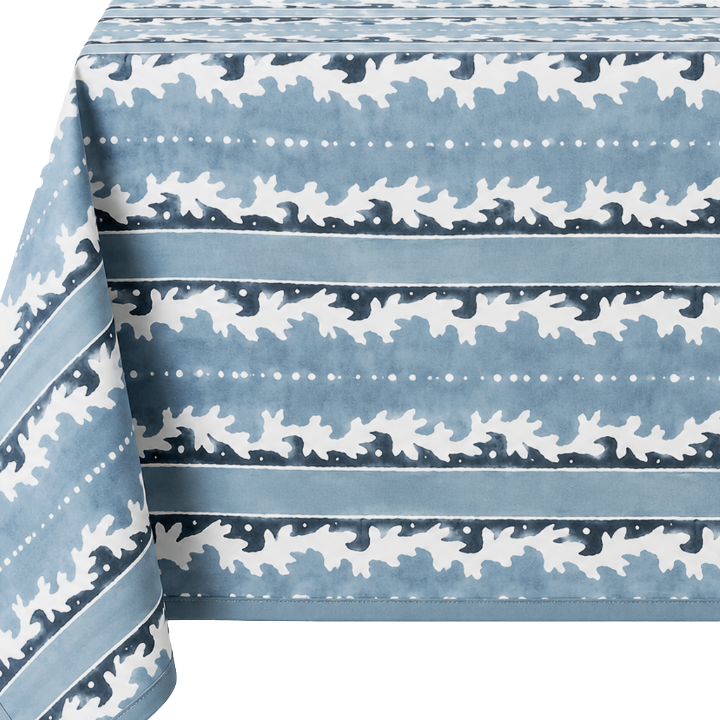 A blue tablecloth with a white repeating pattern of stylized leaves and dotted horizontal stripes, shown draped over the edges against a white background.