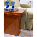 Wooden side table with blue glass goblets and books next to a beige armchair.