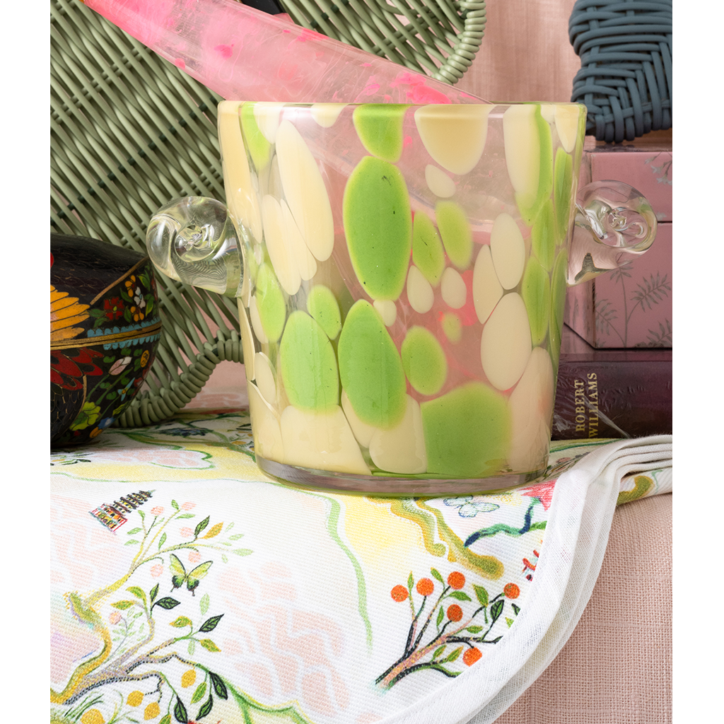 Decorative ice bucket with green and white design on a table with a colorful tablecloth.
