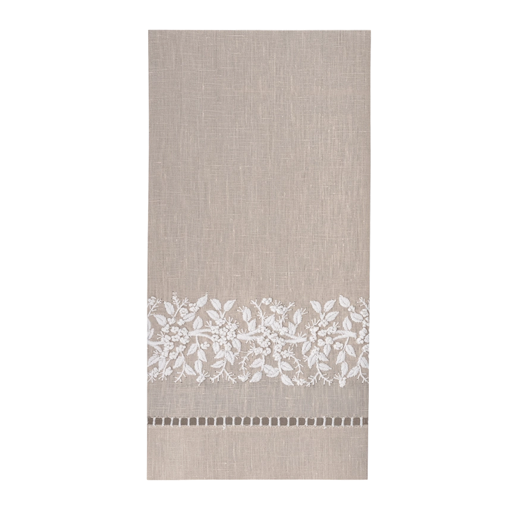 A rectangular beige linen kitchen towel with a white floral lace border and a small geometric pattern near the bottom, shown flat against a white background.