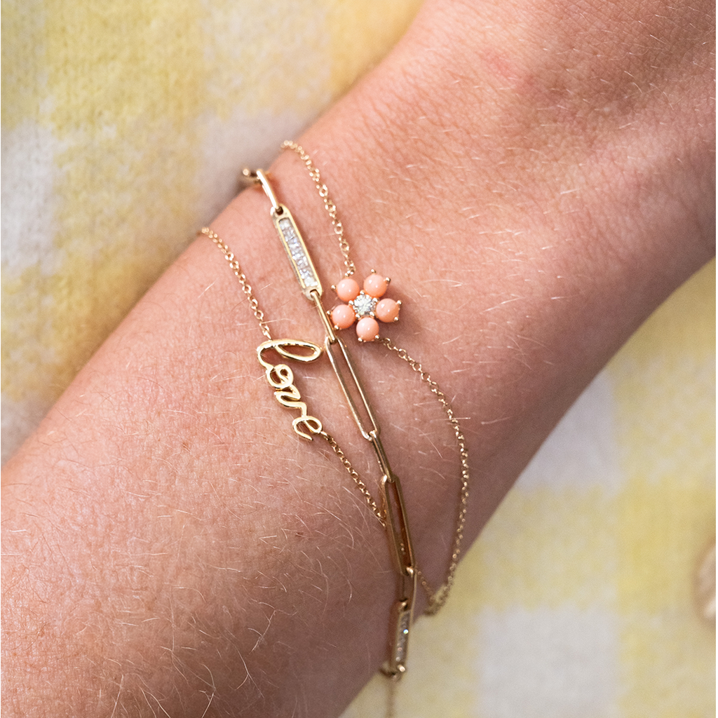 three gold bracelets on a wrist with a yellow background