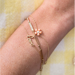 three gold bracelets on a wrist with a yellow background