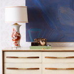 vintage sideboard with artwork and a white and orange lamp