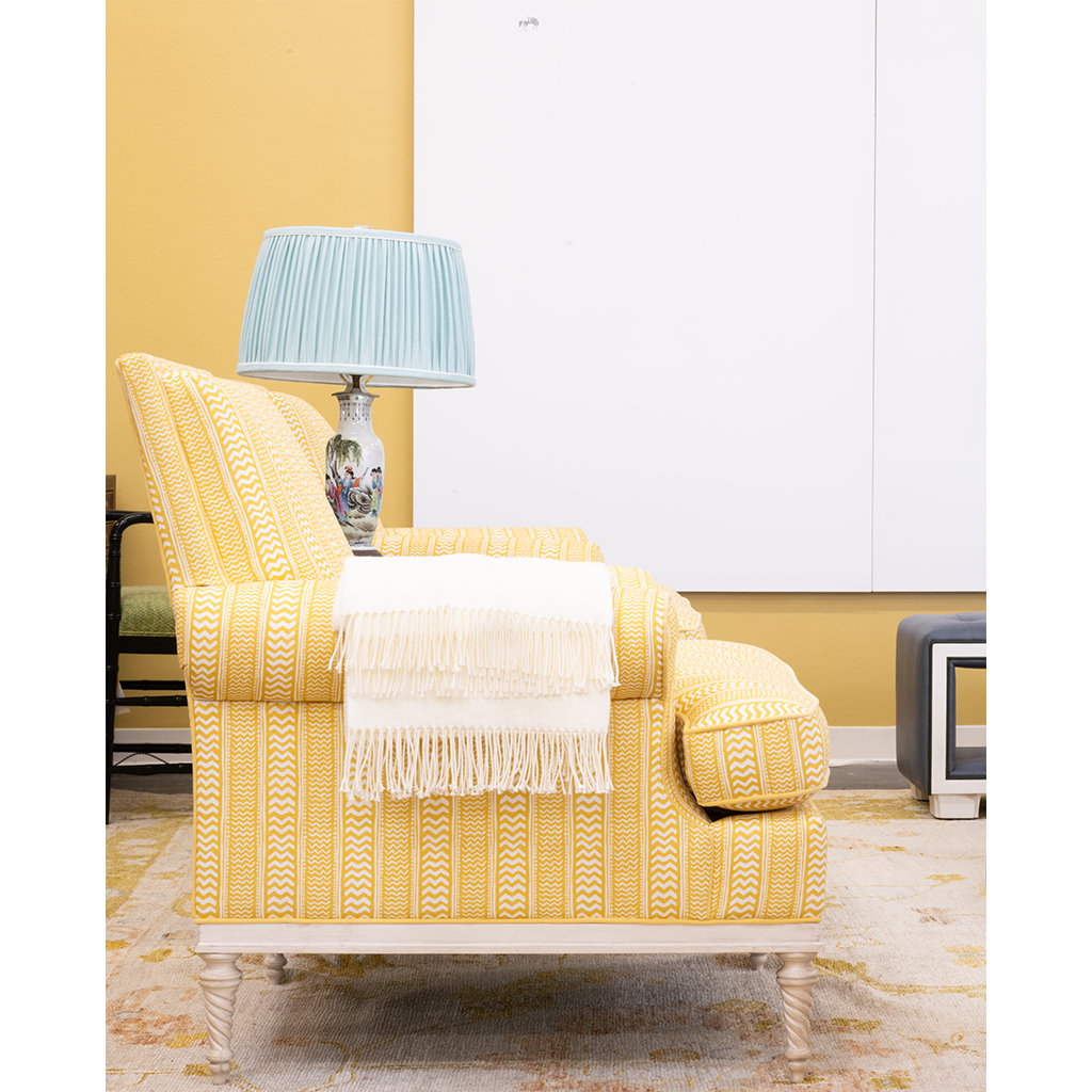 yellow chair next to a blue lamp with white art in the background