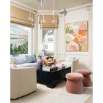 Pink glass bowl with rounded edges sitting on a black coffee table in a bright living room.