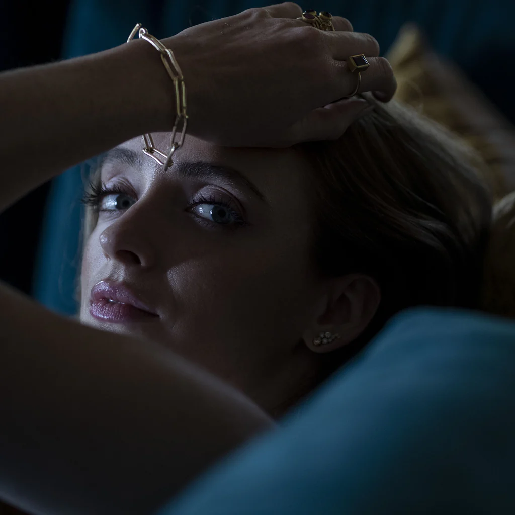 Woman with gold jewelry in a dimly lit room