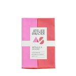 Folded pink and red napkin set with Atelier Saucier branding on a white background