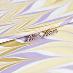 Rose gold earrings on a textured purple and yellow background