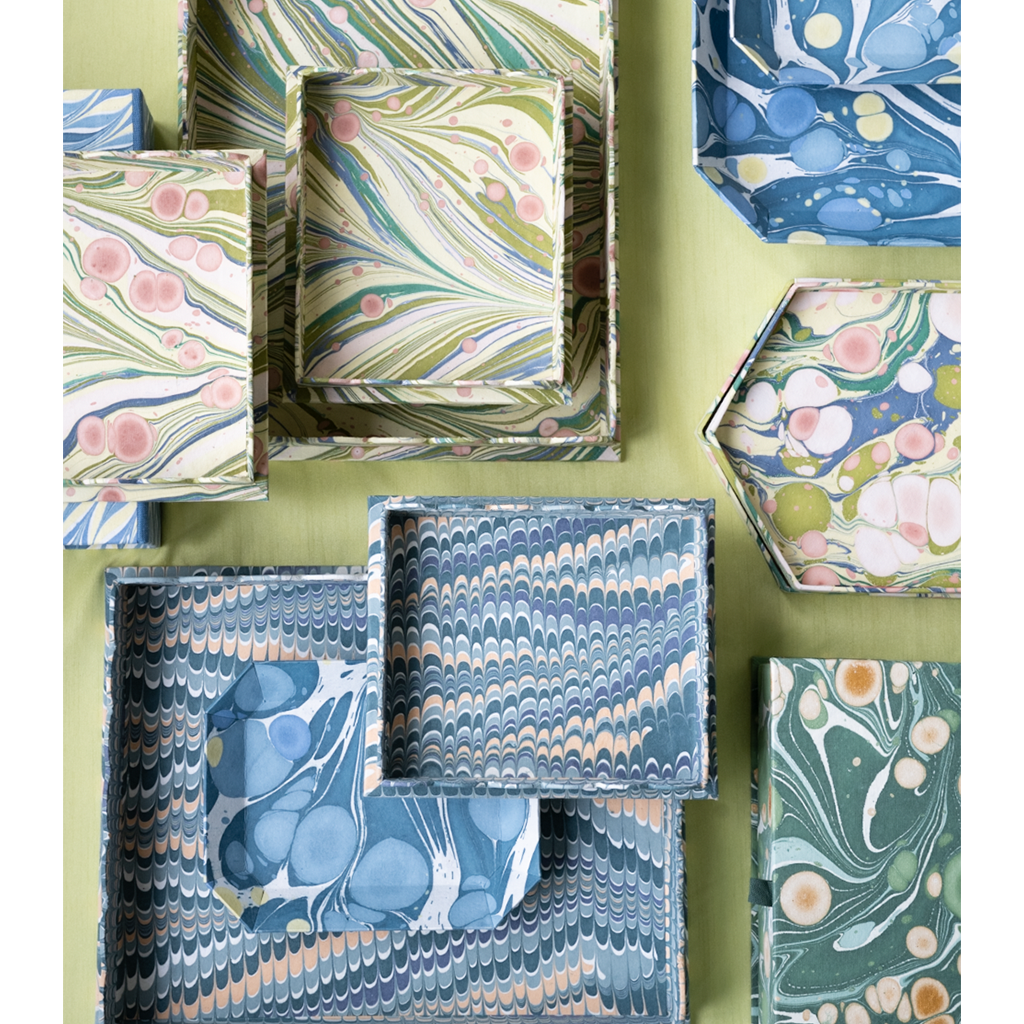 Collection of decorative boxes with marbled patterns on a green background