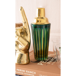 Gold cocktail shaker and book on a table with a neutral background