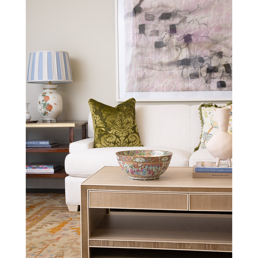Living room with a white sofa, decorative pillow, and coffee table with a bowl.