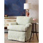 A green and blue chair and a wooden side table with artwork in the background