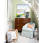 Interior with accent chair, chest topped with vases and lamp, a basket with blankets, and an elephant side table.