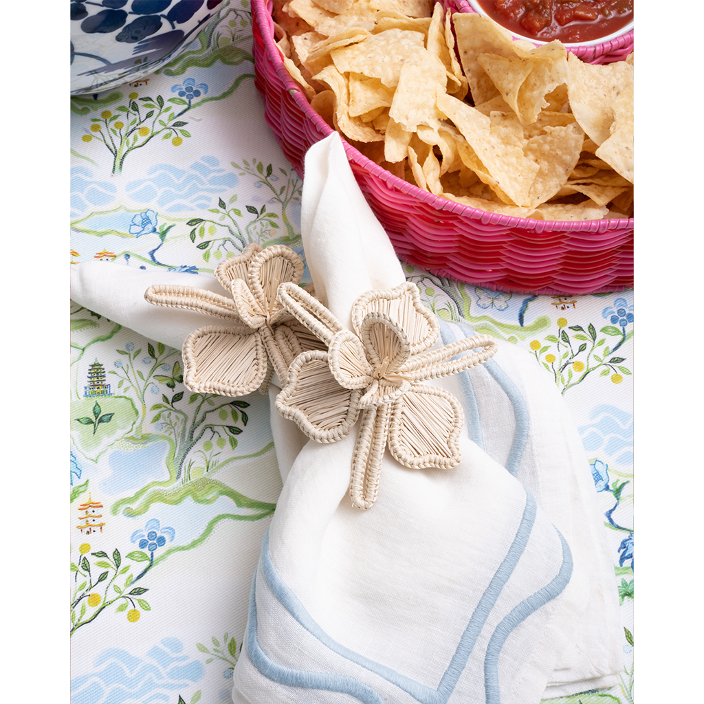 white napkin with flower shaped napkin ring on a blue patterned tablecloth
