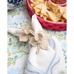 white napkin with flower shaped napkin ring on a blue patterned tablecloth