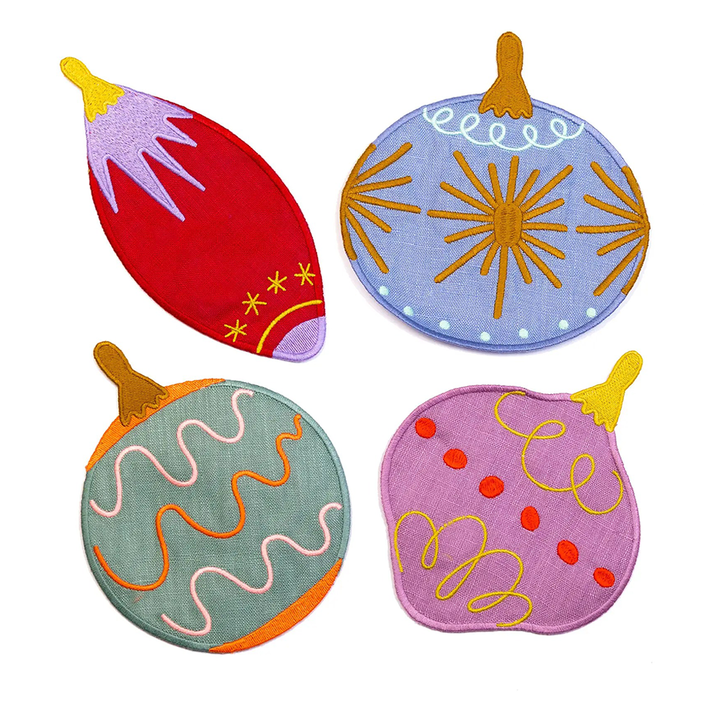 Four colorful Christmas ornament cocktail napkins in purple, orange, green, and blue on a white background.