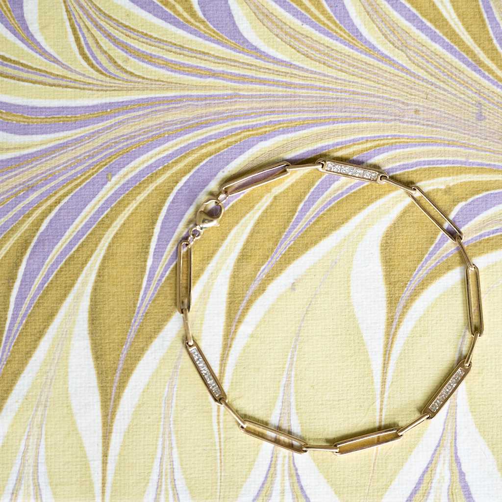 Gold bracelet on a marbled yellow and purple background