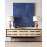 vintage sideboard with artwork and a white and orange lamps