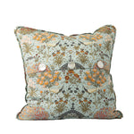 Back of a colorful pillow with a pagoda-like structure, birds, flowers, and botanicals with three mother of pearl button closures on a white background