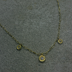 Gold necklace with small round diamond pendants on a gray surface