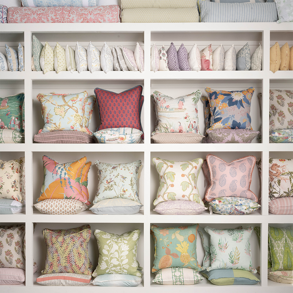 Square decorative pillow with vintage orange and pink tropical floral pattern on white background.