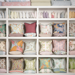 Square decorative pillow with vintage orange and pink tropical floral pattern on white background.