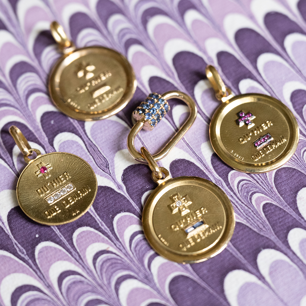 Gold charms with text on a purple patterned background