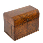 A vintage wooden chest with a hinged lid, featuring rich burl wood grain patterns in warm brown and amber tones, secured with a small metal snap button on the front.