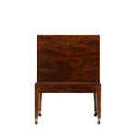 Front view of an antique mahogany cellaret with a richly figured wood grain, a central keyhole, and a clean, rectangular silhouette. The piece stands on straight tapered legs with brass-capped casters, reflecting its elegant early 19th-century design.