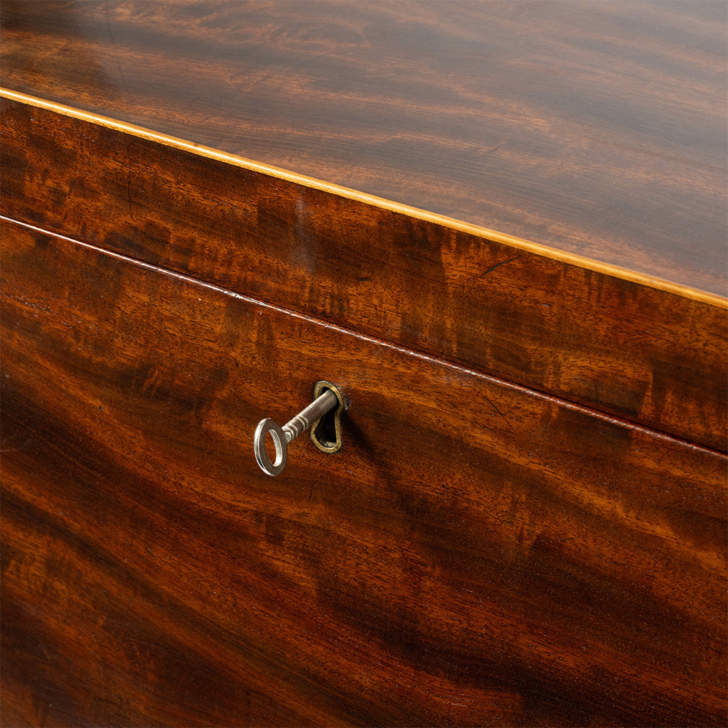 Close-up of a polished dark brown cellaret front with a small metal keyhole lock and a light wood inlay line.